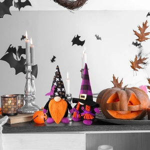 Close-up of Halloween gnomes with orange beards and bat hats among pumpkins and leaves