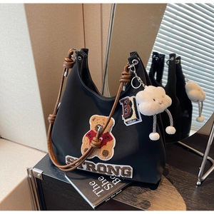 Dettaglio della borsa tote in nylon nero con ricamo orsetto e manici in pelle marrone
