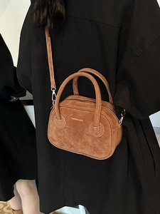 Sac bandoulière en daim marron avec poignées dorées et bandoulière amovible sur mannequin