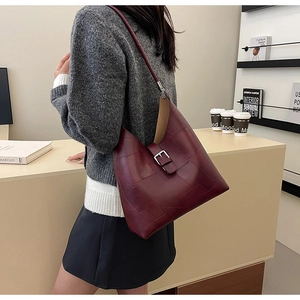 Model wearing a vintage burgundy leather underarm bag with buckle detail in a room