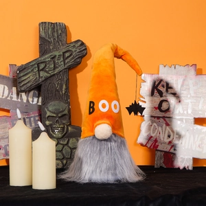 Detail of Halloween gnome plush decoration with BOO hat and bat pendant on orange background