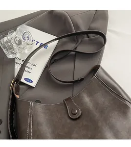 Detail of dark brown leather bucket bag with white contrast stitching and snap button closure