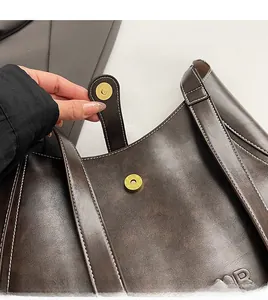 Macro view of vintage brown leather handbag with gold magnetic closure and white stitching