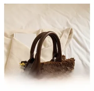 Detail of plush fleece shoulder bag showing smooth leather handle and golden metal hooks