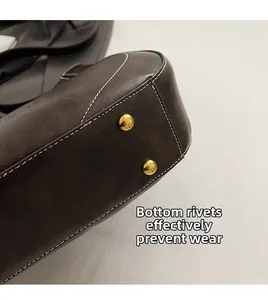 Detail of deep brown leather bag base with gold metal studs and white contrast stitching