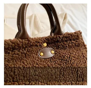 Detail showing deep brown leather handles and golden studs on brown fleece tote bag