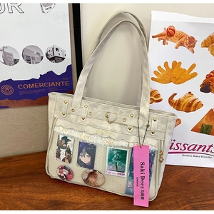 Detail of beige Ita bag featuring heart rivets, lace trim and clear display window