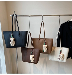 Detail showing four leather tote bags in black, coffee, camel and cream with bear charms