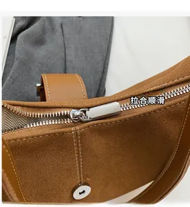 Close-up of smooth metal zipper on brown suede shoulder bag with herringbone lining