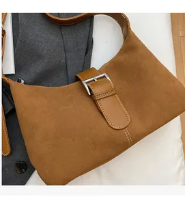 Detail view of brown suede underarm bag featuring silver buckle and white contrast stitching