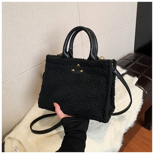 Detail of black faux fur tote bag featuring gold hardware and leather handles