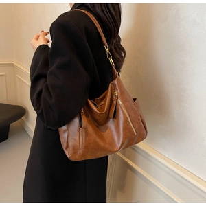 Detail view of brown leather tote bag with stylish zipper accent and gold hardware