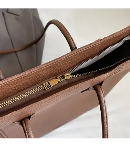Detail of high-quality smooth metal zipper and lychee grain leather on a brown tote bag