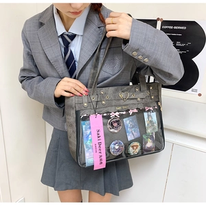 Macro detail of ita bag with clear window featuring anime badges and decorative bows