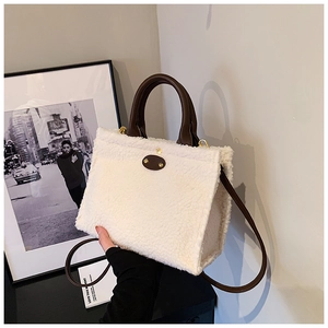 Detail of white plush tote bag texture with brown leather strap and golden rivet accent