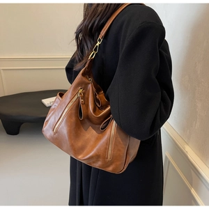 Detailed view of brown leather hobo shoulder bag with decorative gold double zippers