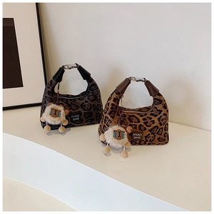 Detail view of leopard print handbags featuring leather straps and plush sheep charms