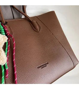 Detailed macro of dark brown lychee leather texture and woven cord on a tote bag