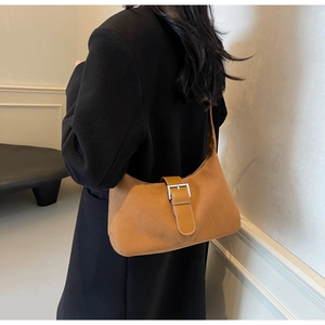 Brown suede half-moon shoulder bag with buckle detail worn with a black wool coat