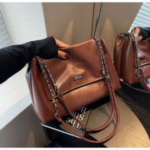 Detail der Vintage Tragetasche in Dunkelbraun mit Kettenriemen und Metall Logo Plakette