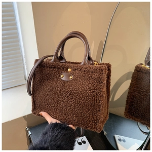 Detail der braunen Plüschtasche mit Ledergriffen und goldfarbenen Nietenverzierung