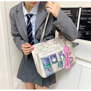 Detail of beige ita bag with transparent window showing anime pins and lace trim