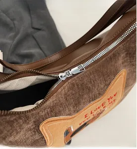 Close-up of smooth silver metal zipper and brown corduroy fabric with embroidery detail