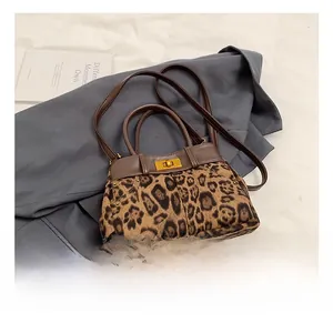 Macro view of leopard print texture, brown leather trim and golden metal clasp lock