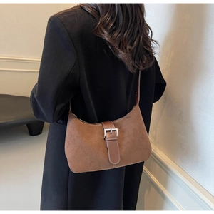 Detail of brown suede shoulder bag featuring contrast stitching and silver metal buckle