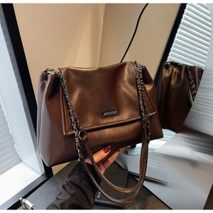 Detail der dunkelbraunen Leder-Shopper-Tasche mit Metall-Logo und Ketten-Schultergurt