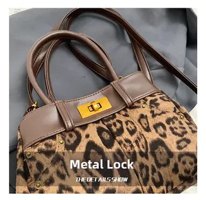 Close-up of golden hardware swivel lock on leopard print plush handbag with leather trim