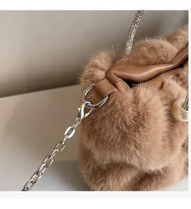 Détail du tissu en peluche marron clair avec boucle en perle de luxe et chaîne argentée