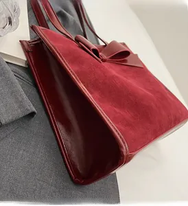 Detail of dark red tote bag showing contrast between matte suede and glossy patent leather