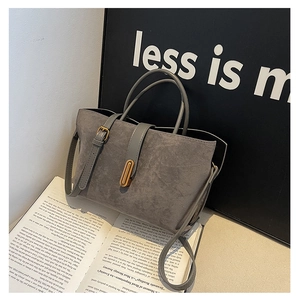 Detail of grey suede tote bag with leather straps and elegant gold metal oval lock