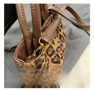 Detailed close-up of golden metal swivel hook and stitching on brown leopard bag