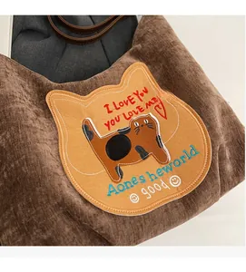 Macro detail of brown corduroy tote bag featuring cute cat patch and leather handle