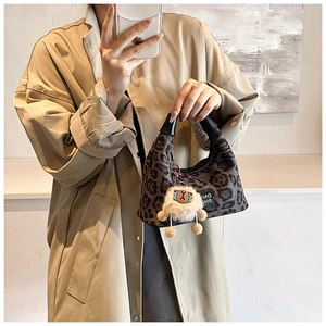 Detail of leopard print crossbody bag with cute alpaca charm and black leather handle
