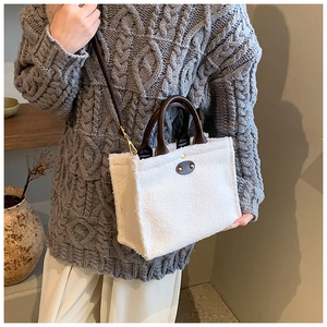 Detail of white fluffy tote bag with brown leather handles and adjustable shoulder strap
