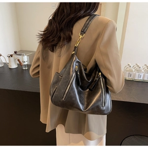 Close-up of a black faux leather tote with silver zippers and golden snap hooks