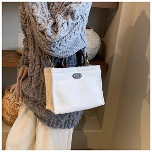 Detail view of white plush tote bag with brown leather handles and gold metal hardware