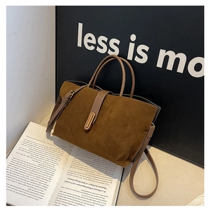 Close-up of brown suede tote bag with leather strap and brass buckle detail