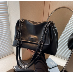 Detailansicht der schwarzen Ledertasche mit Markenlogo und schicker Metallkette