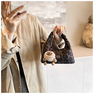 Detail of leopard print handbag with black leather handles and cute sheep pendant