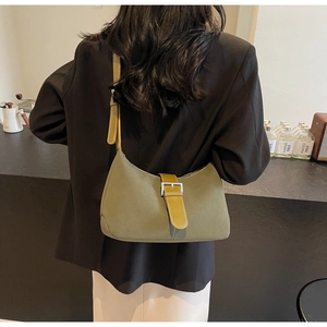 Detail view of olive green shoulder bag with brown leather strap and silver metal buckle