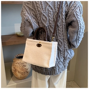 Detail of white faux shearling tote bag with brown leather handles and adjustable strap