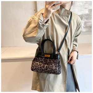 Detail view of the gold twist lock and leopard print texture on this crossbody bucket bag