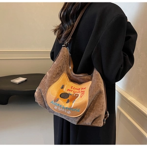 Brown corduroy tote bag with cat embroidery shown on model in a minimalist room