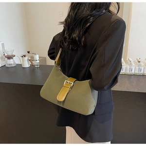 Close-up of olive green crossbody bag with contrast buckle detail on a cafe background