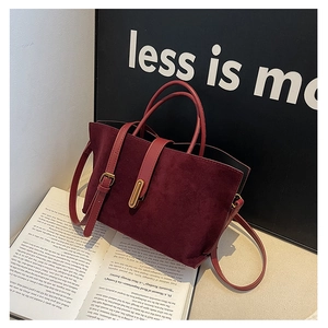 Detail of burgundy frosted leather tote bag with elegant gold buckle and retro book scene