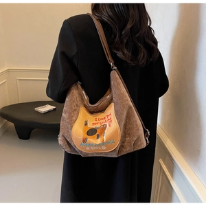 Detail of a brown corduroy shoulder bag featuring a cute cat patch and leather strap